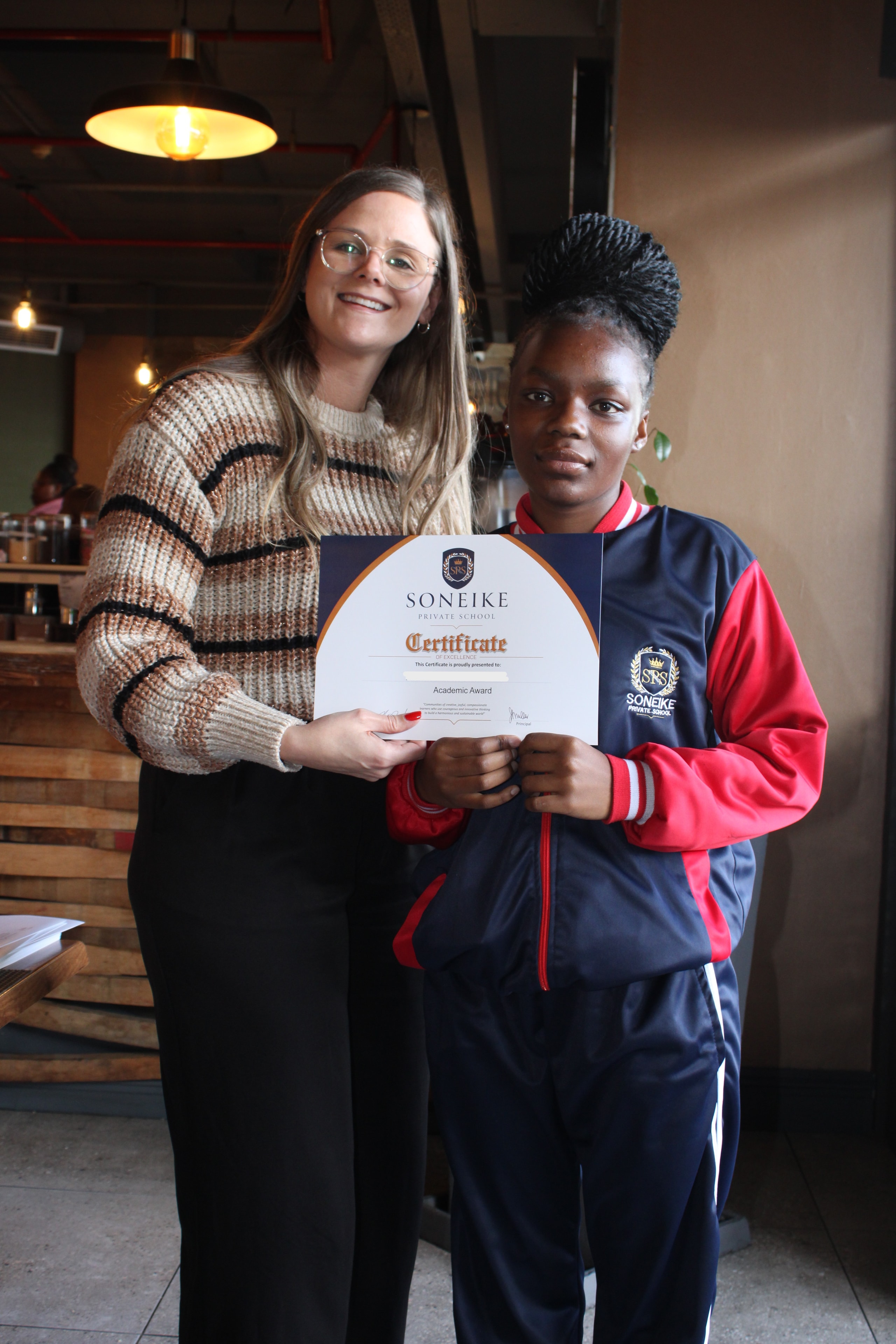 Soneike learner proudly receiving her Academic Award certificate at the termly awards ceremony