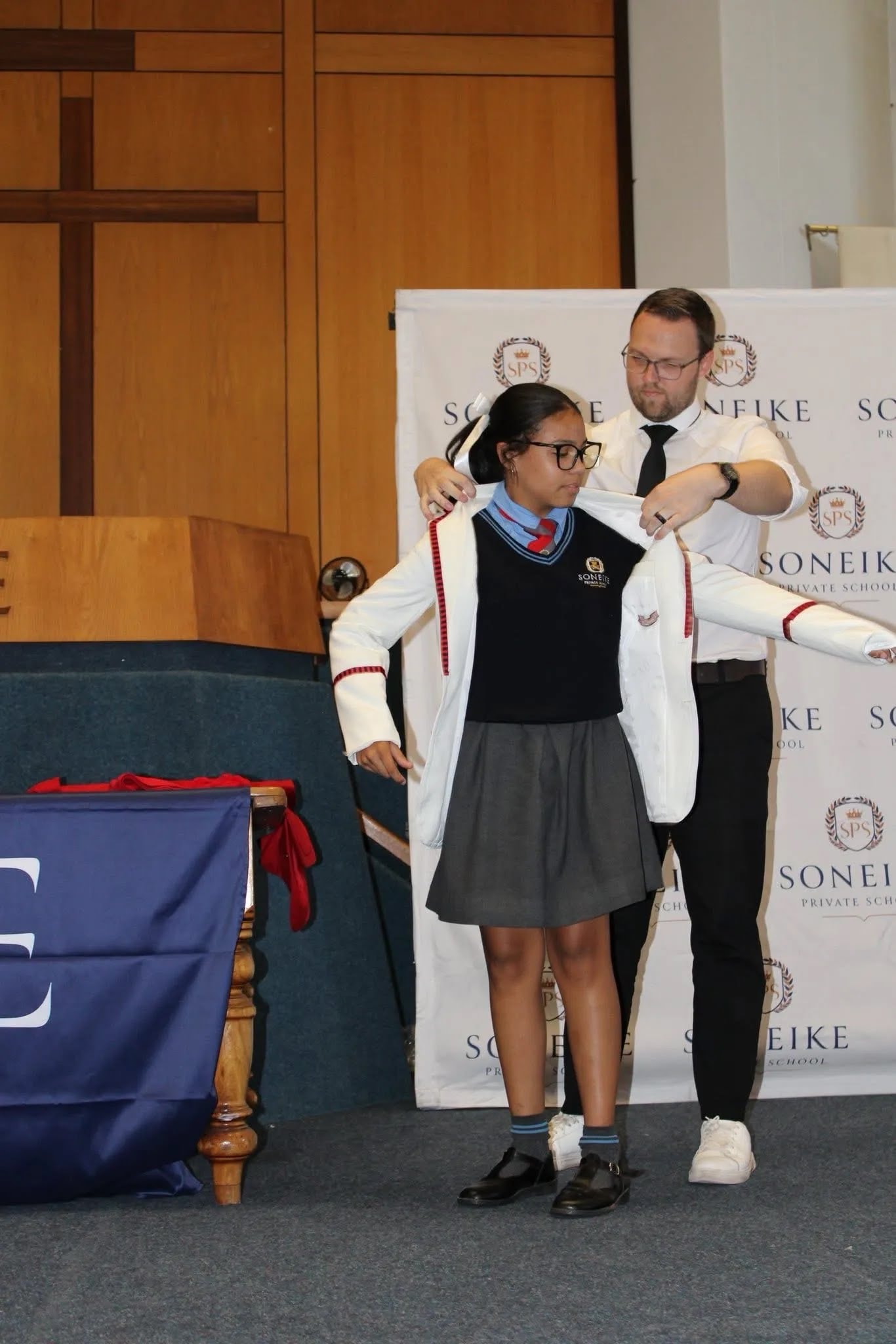 Soneike STEM School learner being presented with her white blazer on stage