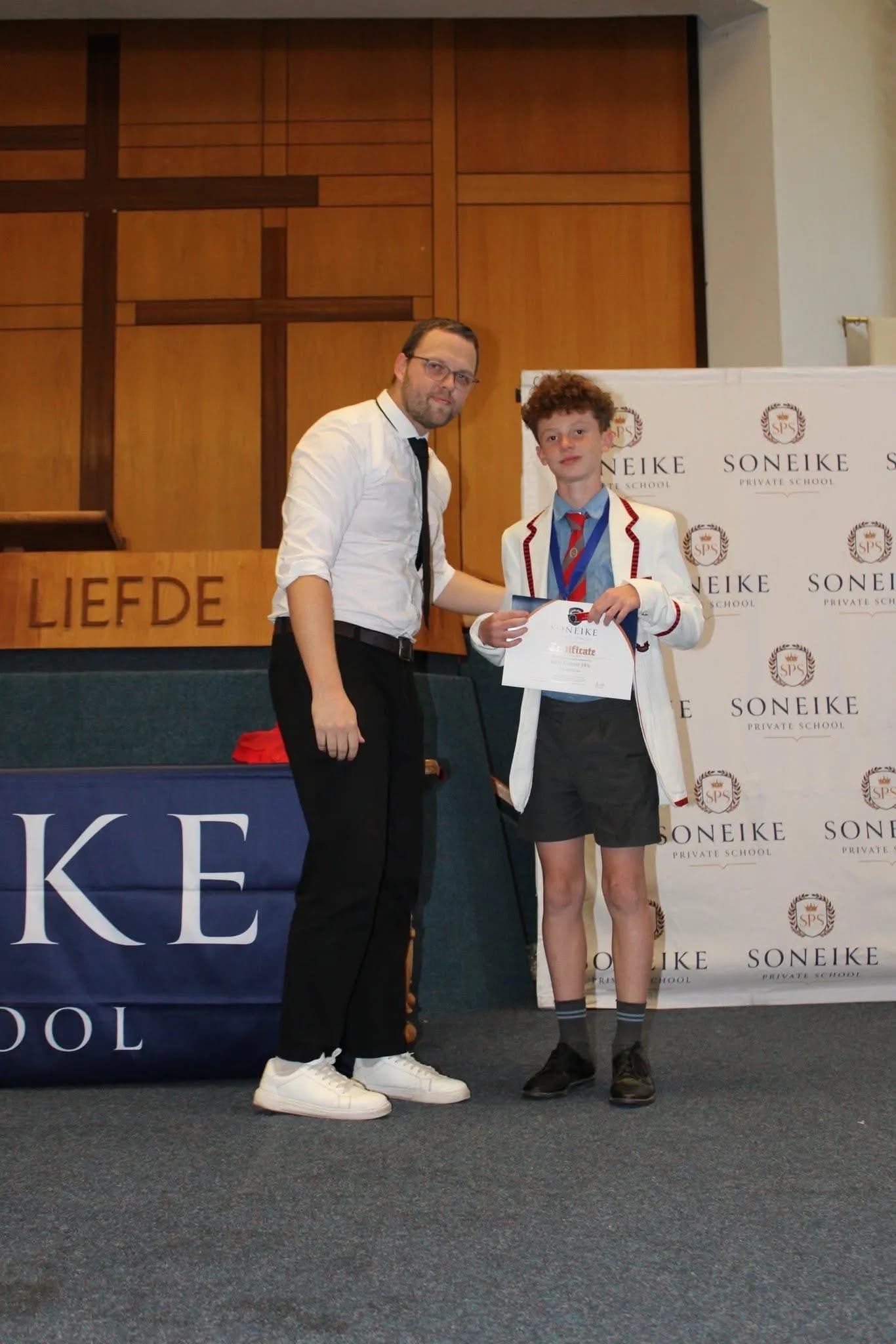 Soneike STEM School learner in white blazer receiving his certificate