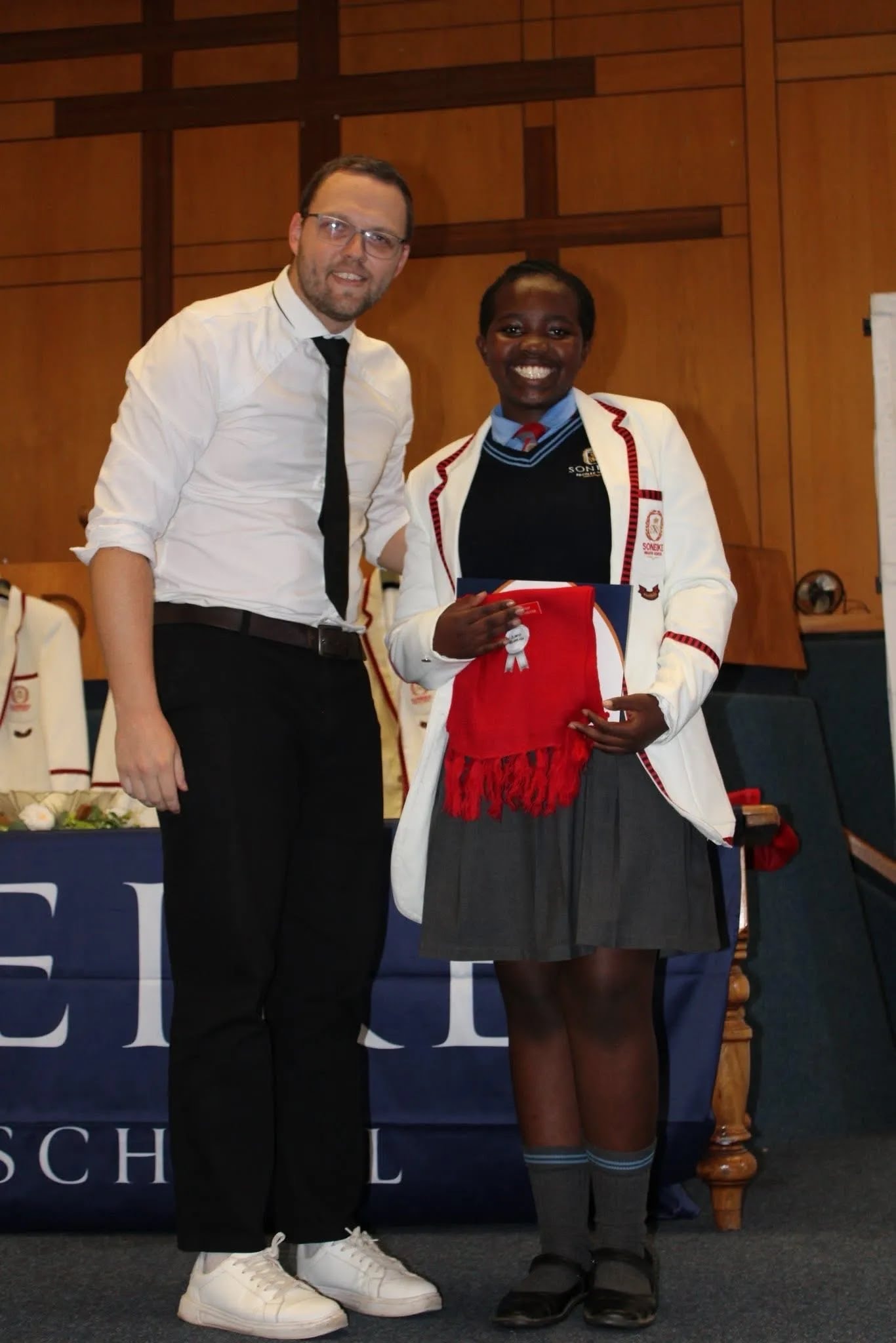 Soneike STEM School learner in white blazer proudly holding her award and sash